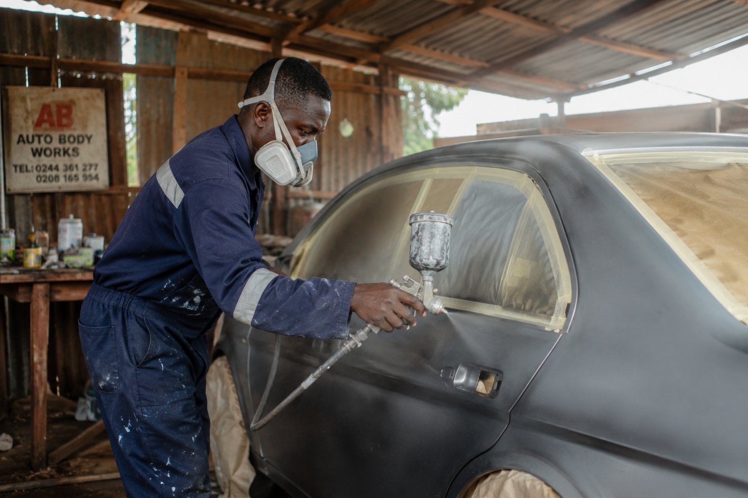 Technician spray-painting a car body panel